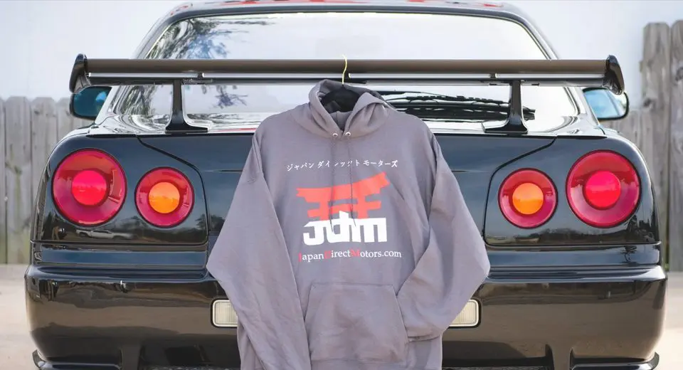 A gray hoodie hanging on the back of a car.