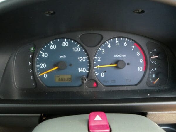 A car dashboard with two different speedometers and one pink mouse.