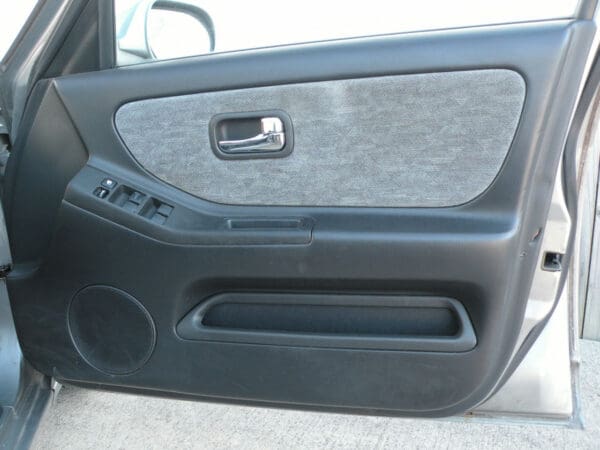 A car door with some wood trim and a black handle