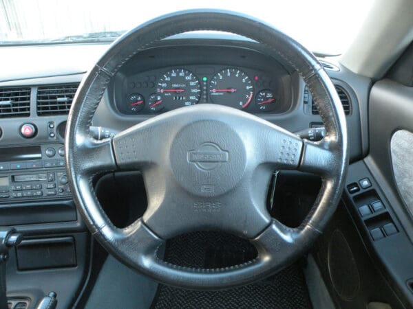 A steering wheel of a car with the dashboard turned to the left.