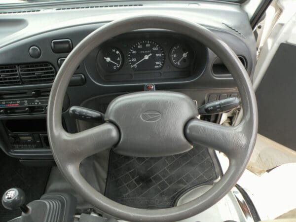 A steering wheel of an automobile with the dashboard and dash.