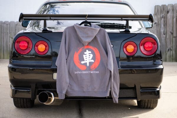 A gray hoodie hanging on the back of a black car.