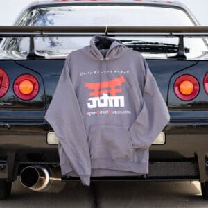 A gray hoodie hanging on the back of a car.