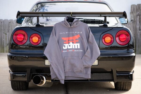 A gray hoodie hanging on the back of a car.