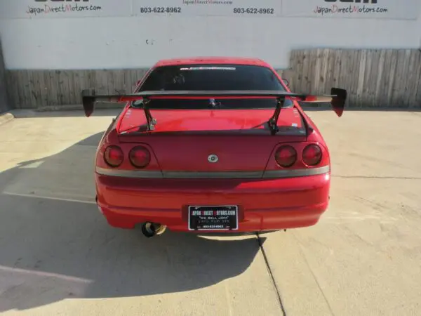 Red Nissan Skyline R33 with a spoiler.