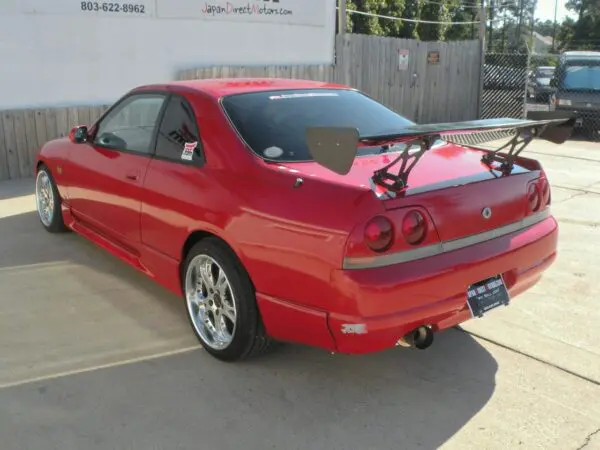 Red Nissan Skyline R33 with wing.