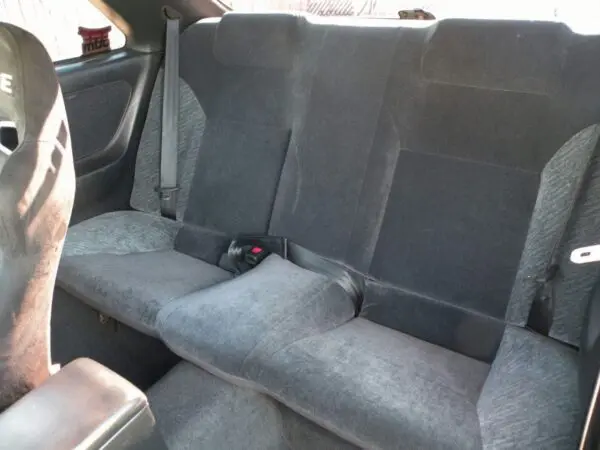 Gray fabric car backseat with seatbelts.