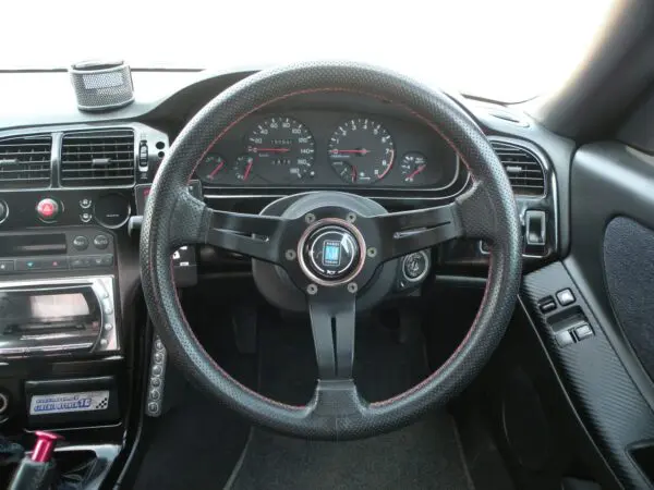 Black leather steering wheel in car interior.