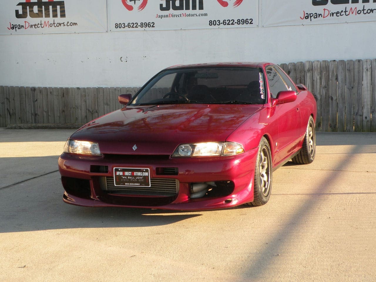 Red Japanese car parked in front of a building.