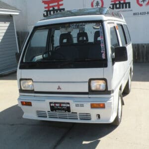 White Mitsubishi minivan parked in driveway.