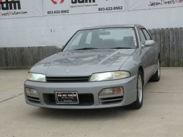 Silver Nissan Skyline R33 sedan.