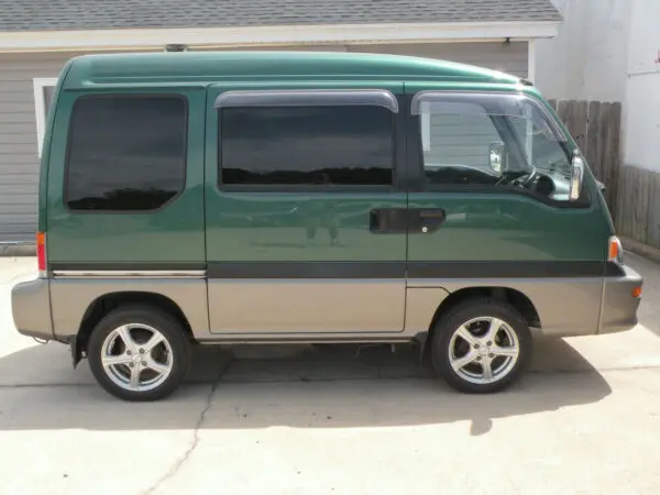 Green minivan parked on concrete.