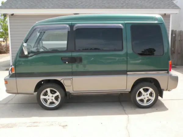 Green minivan parked on concrete.