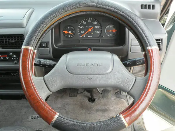 Subaru car interior with wooden steering wheel.