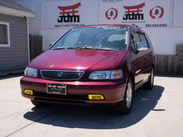 Red Honda Odyssey minivan parked outside.