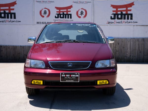 Red Honda Odyssey minivan front view.