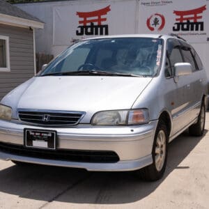 Silver Honda Odyssey minivan parked on asphalt.