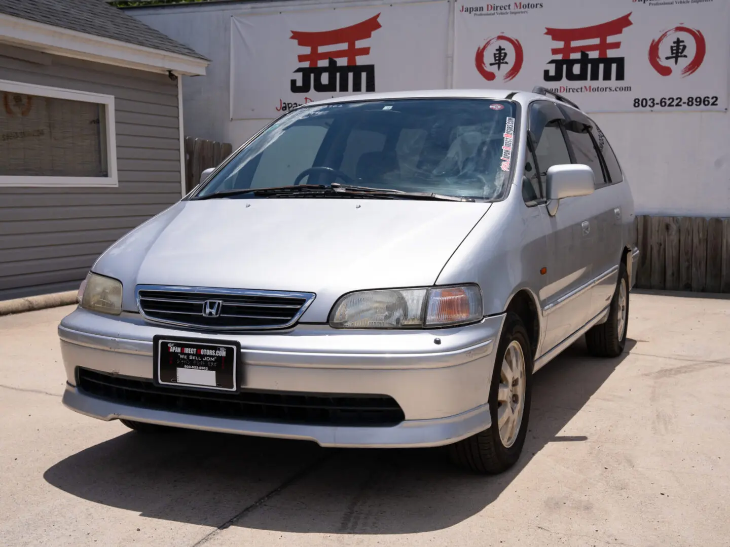 Silver Honda Odyssey minivan parked on asphalt.