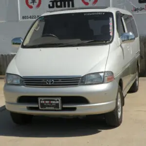 White Toyota minivan parked in front of a fence.