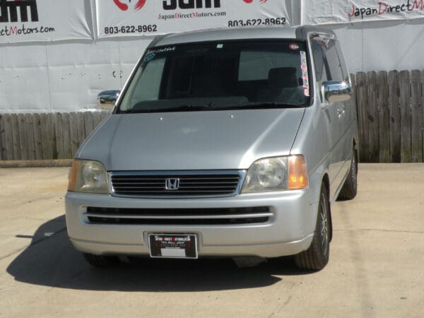 Silver Honda minivan parked on asphalt.