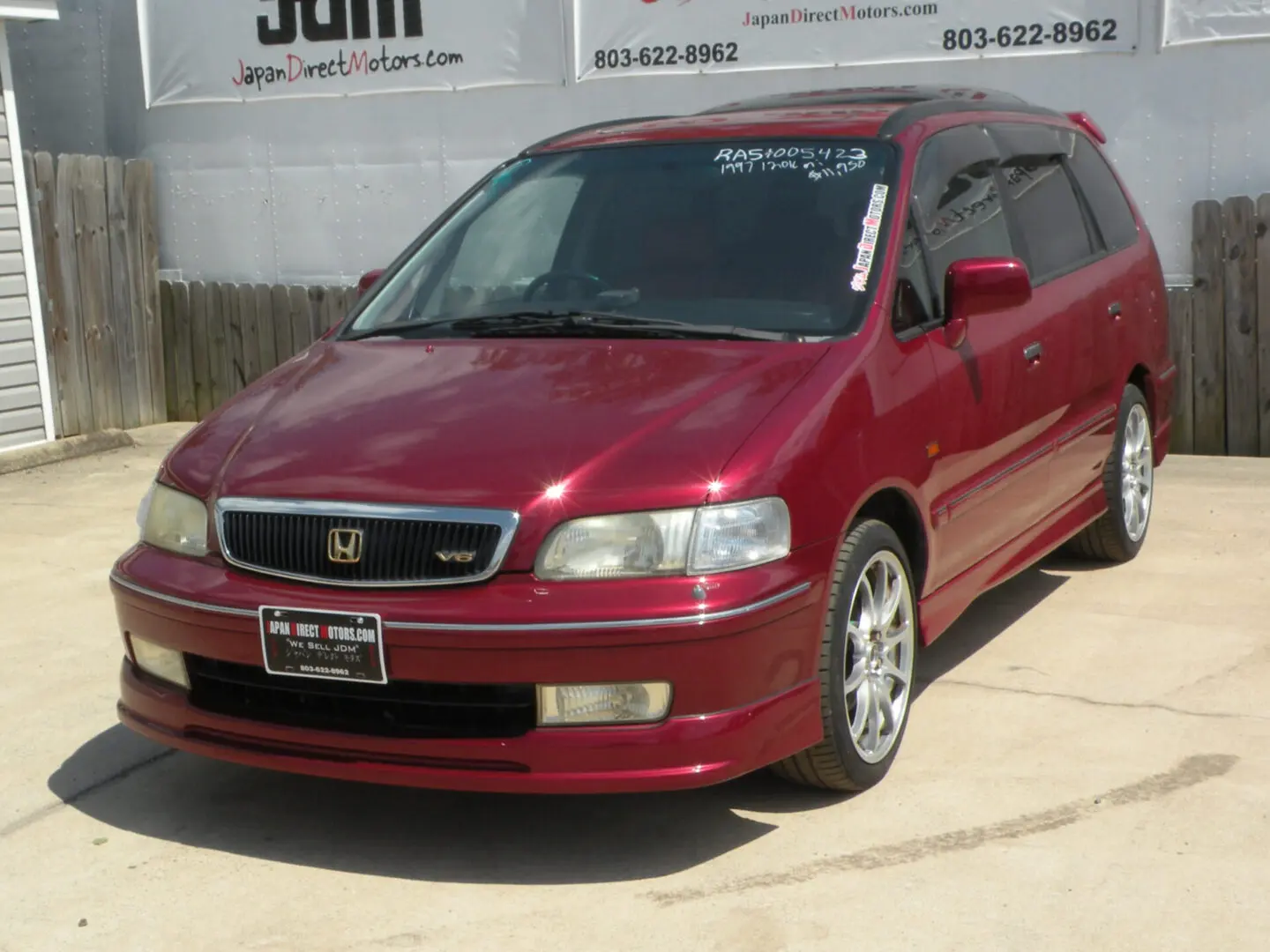 Red Honda Odyssey minivan parked outside.