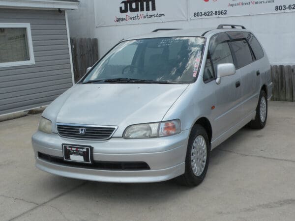 Silver Honda Odyssey minivan parked on pavement.