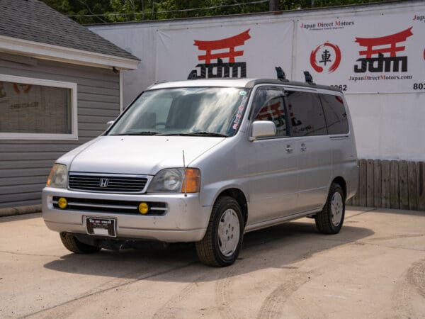 Silver Honda minivan parked in front of a building.