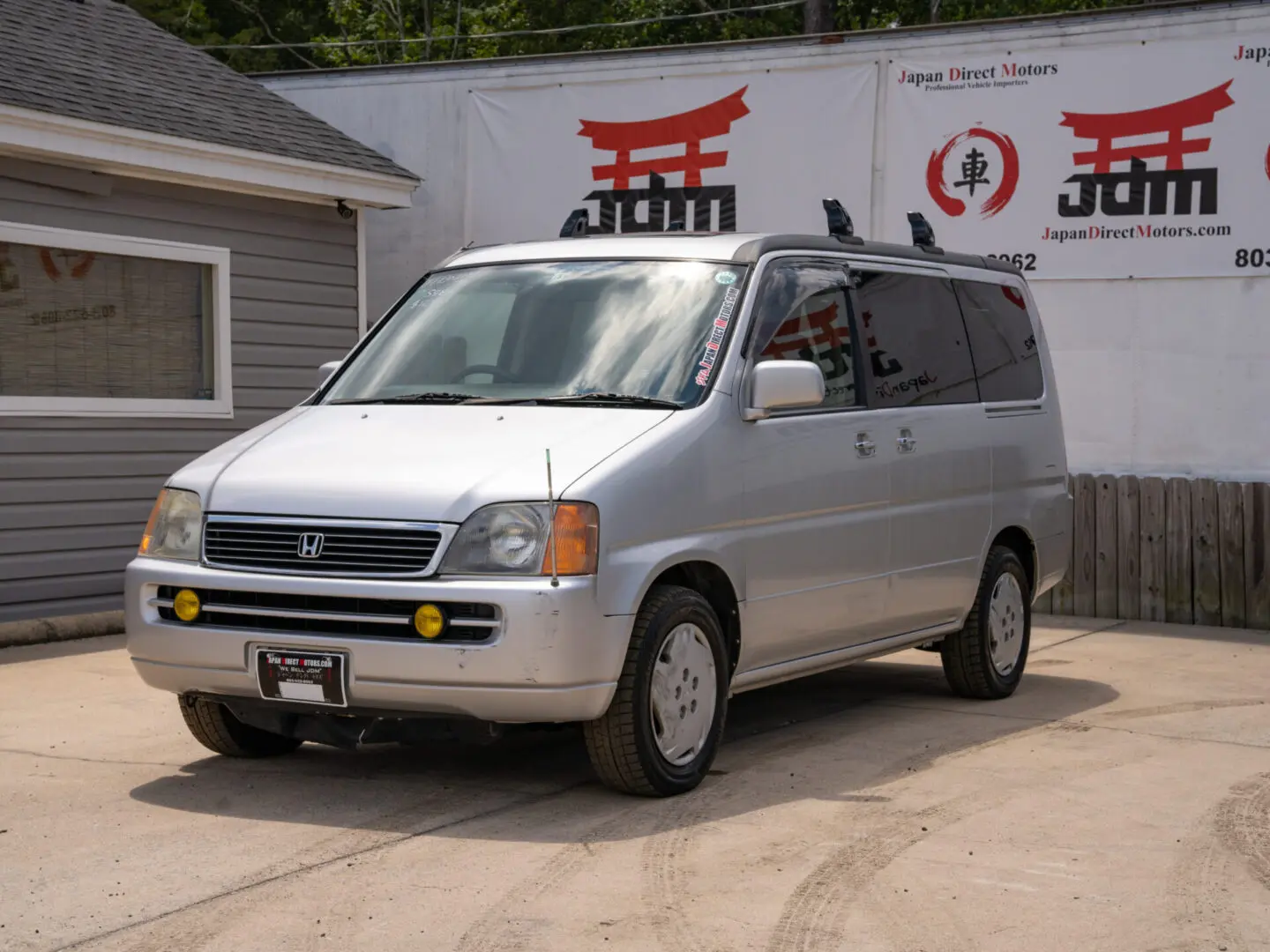 Silver Honda minivan parked in front of a building.