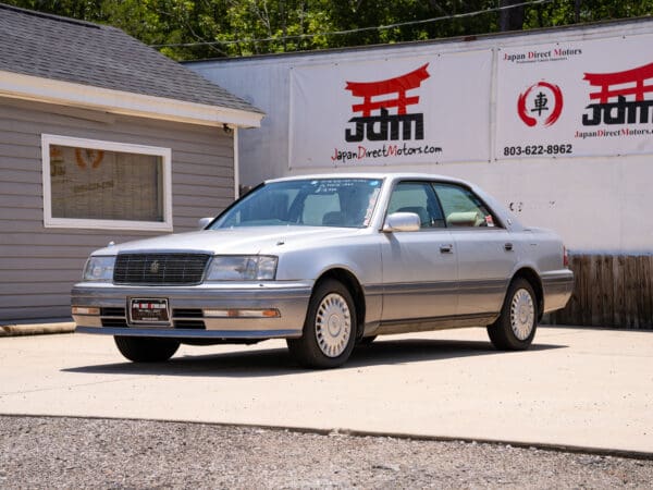 Silver Toyota Crown sedan parked in front of a building.