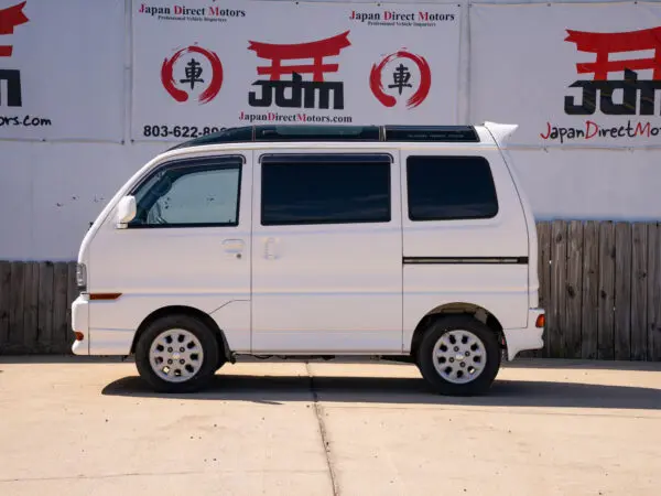 White van parked in front of a wall.