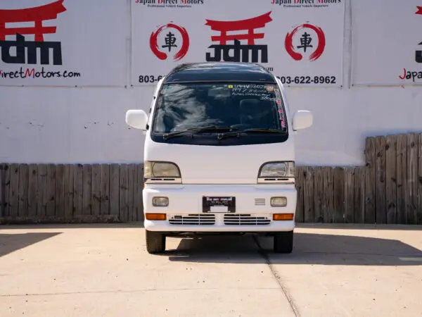 White Japanese van parked in front of a building.