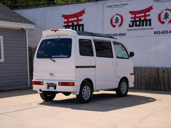 White van parked in front of a dealership.