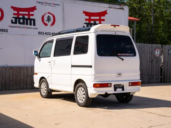 White Japanese minivan with rear spoiler.