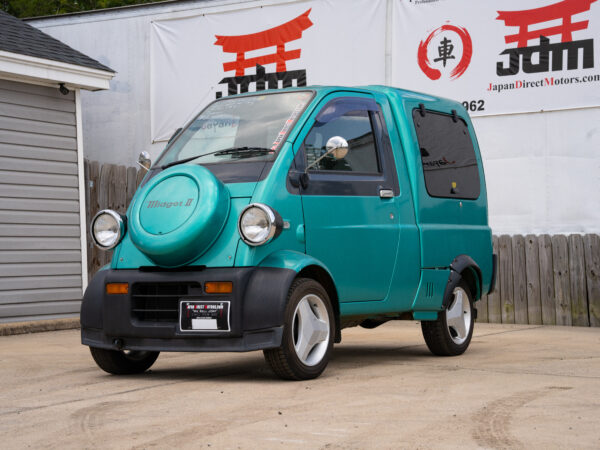 Teal Midget II mini van parked outside.