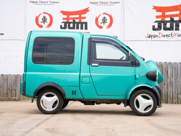 Teal Japanese mini van parked outside.