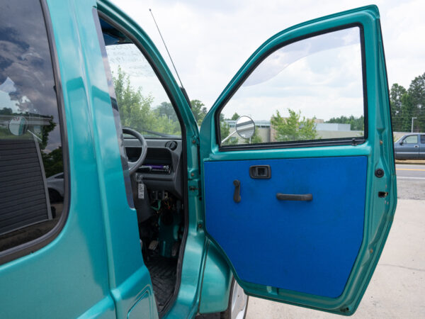 Teal minivan with open door and blue interior.