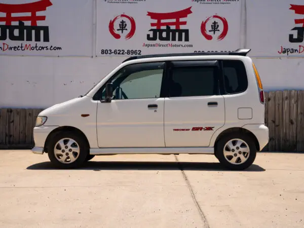 White Japanese minivan parked on pavement.