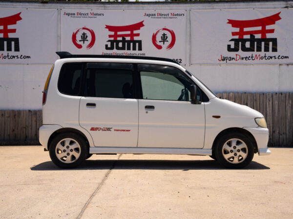 White Japanese car parked outside a dealership.