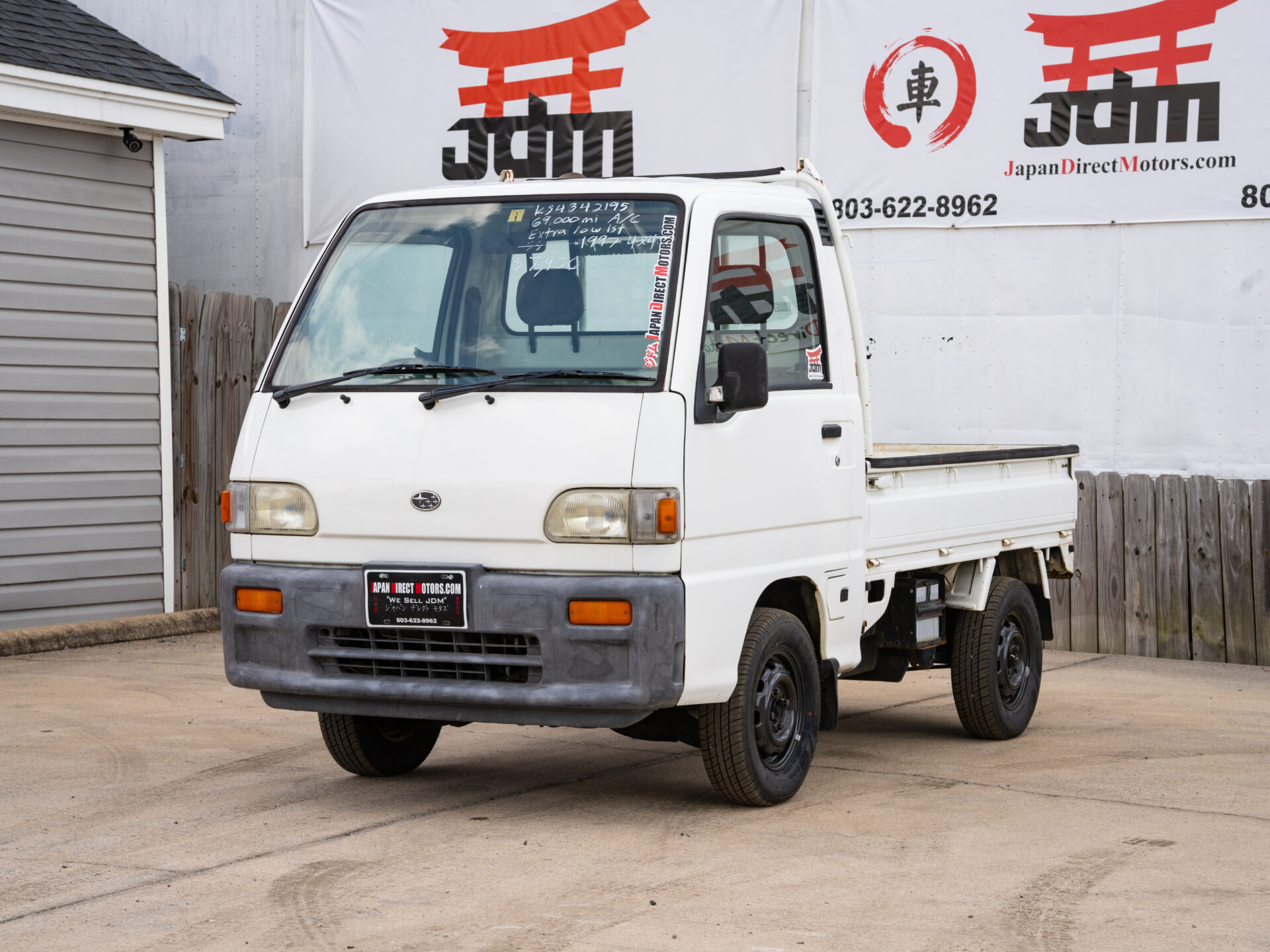 White Japanese mini truck parked on asphalt.