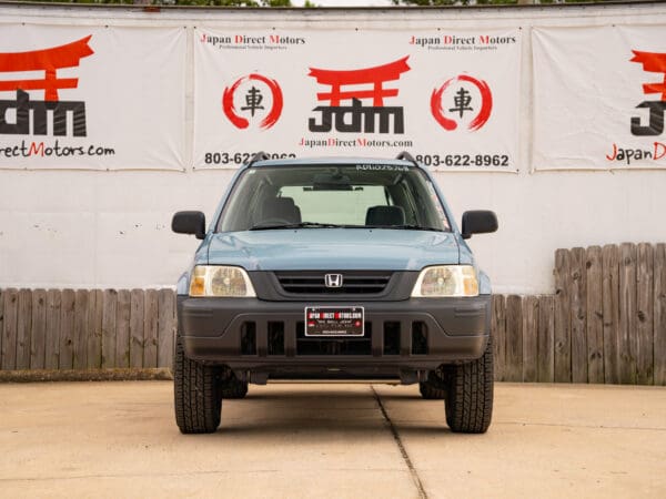 Blue Honda CR-V in front of a sign.