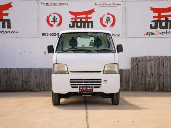 White Japanese van in front of a sign.