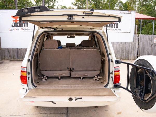 White SUV with open trunk and spare tire.