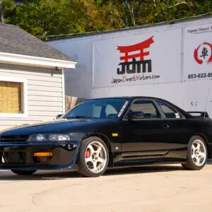 Black Nissan Skyline R33 parked in front of building.