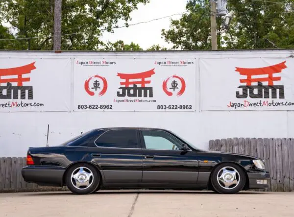 Black Lexus LS400 parked in front of a dealership.