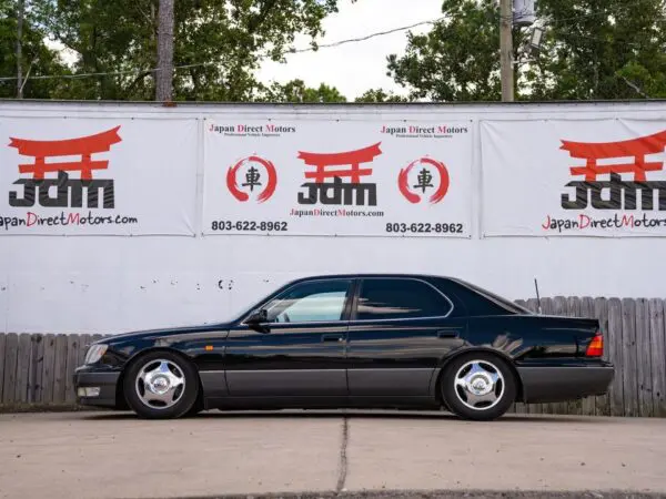 Black Lexus LS400 parked in front of a dealership.