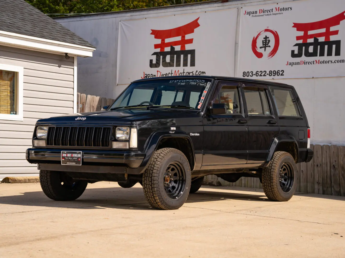 Black Jeep Cherokee in front of dealership.