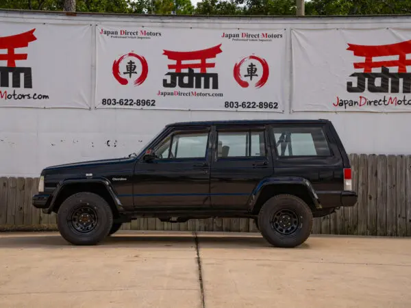 Black Jeep Cherokee parked in front of a sign.