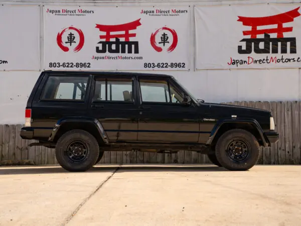 Black Jeep Cherokee parked near a wall.