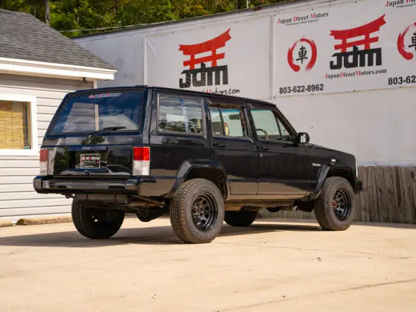 Black Jeep Cherokee parked in front of a building.