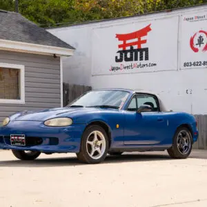 Blue Mazda Miata convertible parked outside.